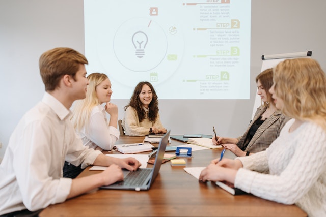 business-professionals-discussing-marketing-strategies-around-a-table-with-a-projector-and-computer